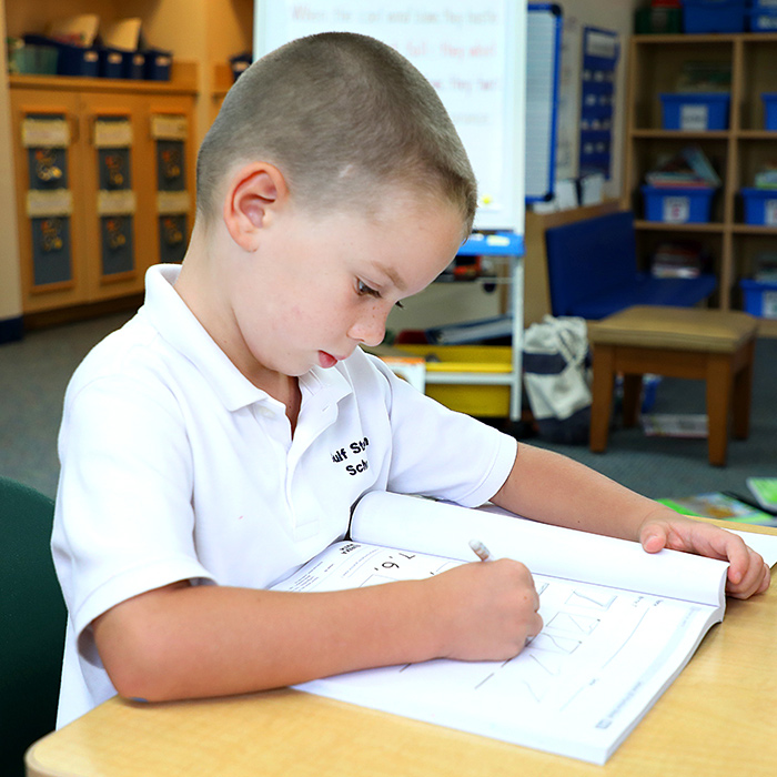 Private school Kindergarten student writing in notebook