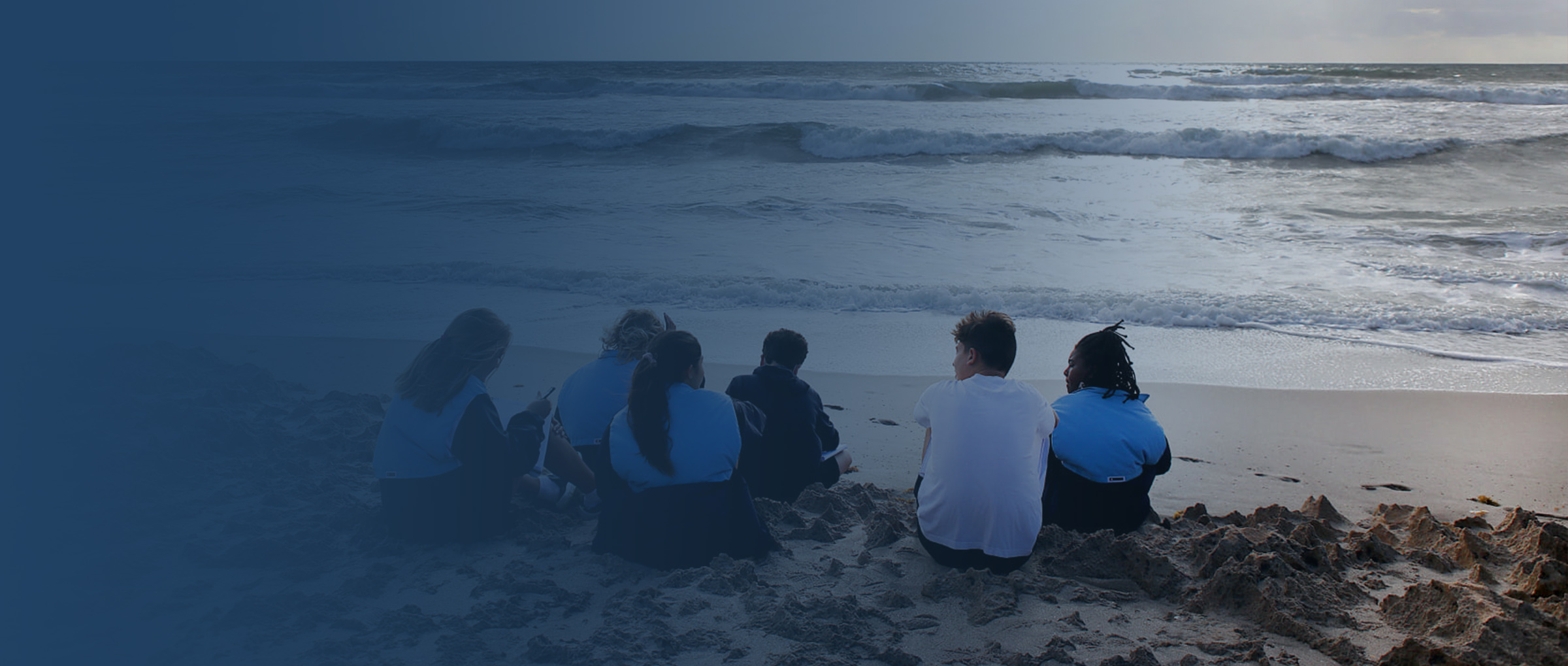 gulf stream school students sitting on the beach
